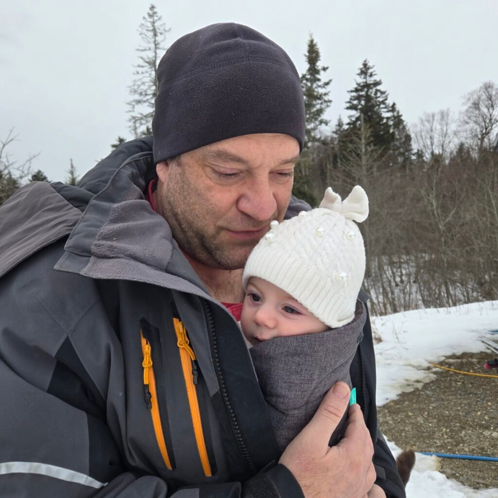 Father holding his baby on a snowy winter day at the farm
