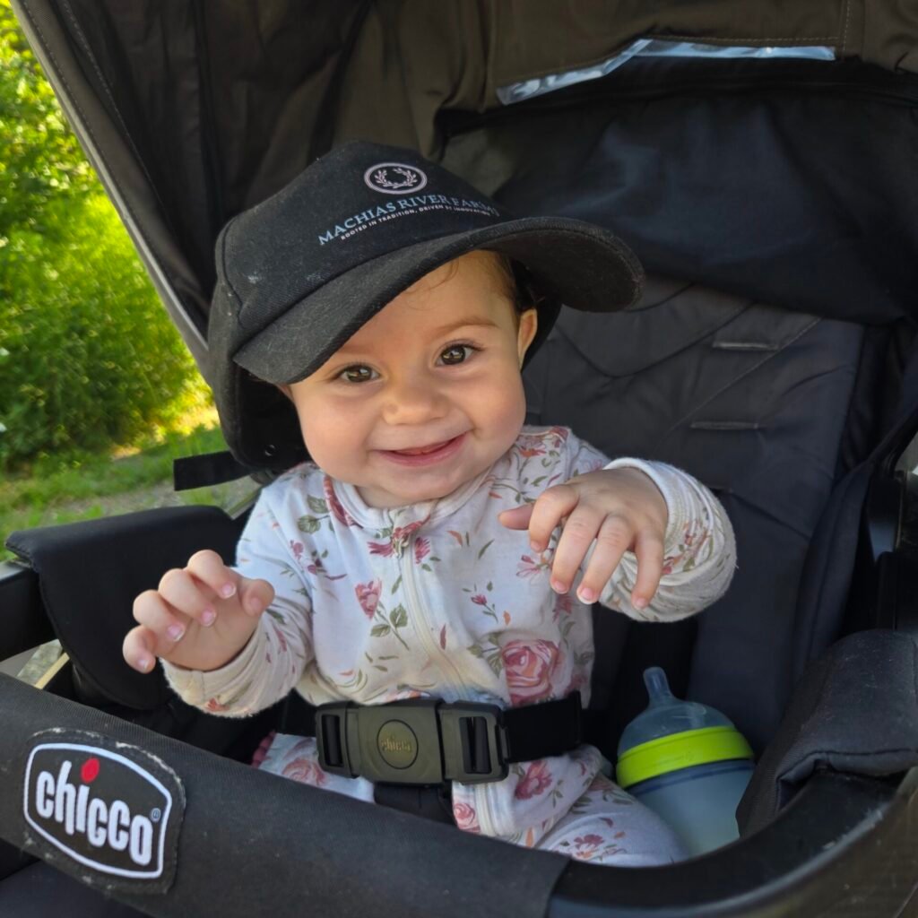 Smiling baby in a stroller wearing a farm cap