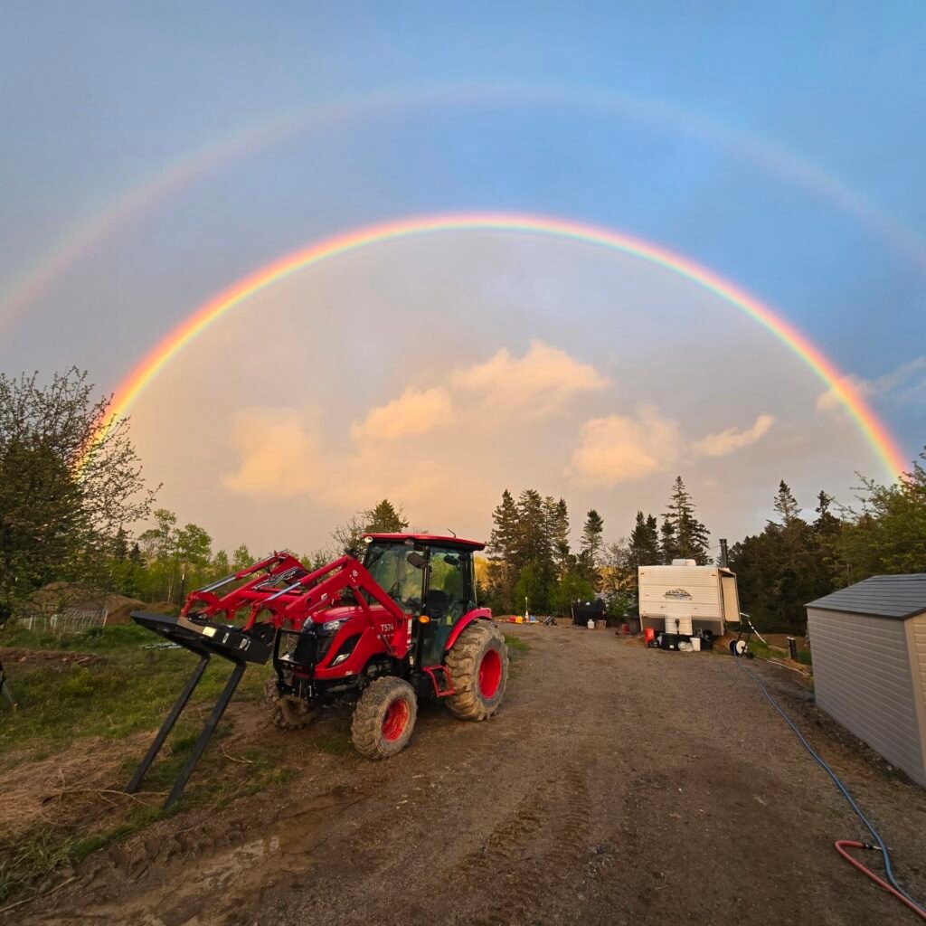 Rainbow over a red tractor on the farm road
